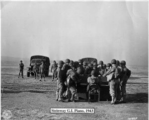 American G.I.s in WWII gathered around a Victory Vertical in an open field. Looks like a sing-a-long to me